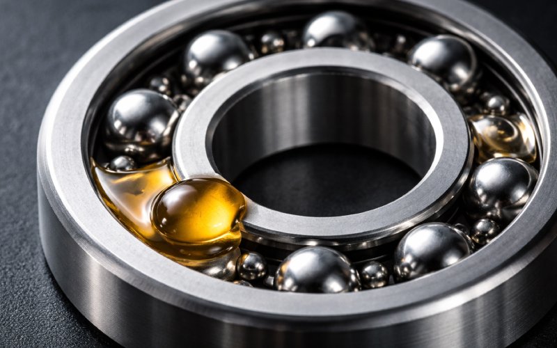 Macro shot of a steel ball bearing with a single drop of amber oil